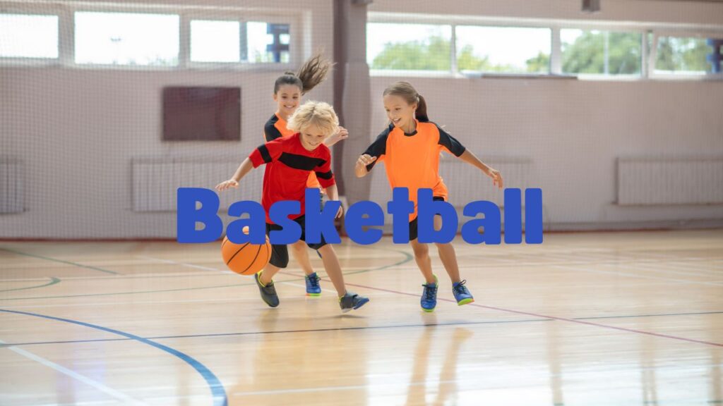 Three children playing basketball in a gymnasium.